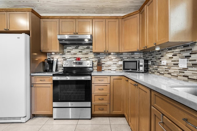 kitchen featuring stainless steel electric range oven, decorative backsplash, white refrigerator, light tile patterned floors, and light stone countertops