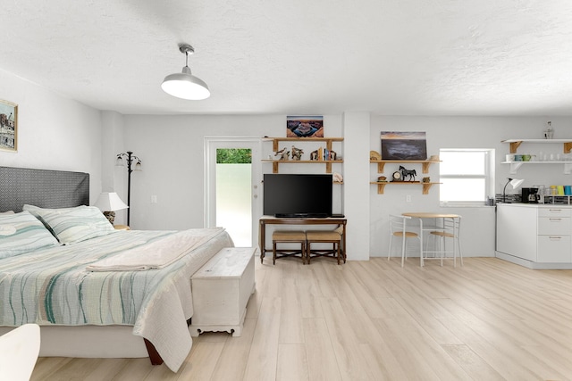 bedroom featuring a textured ceiling, access to exterior, and light wood-type flooring