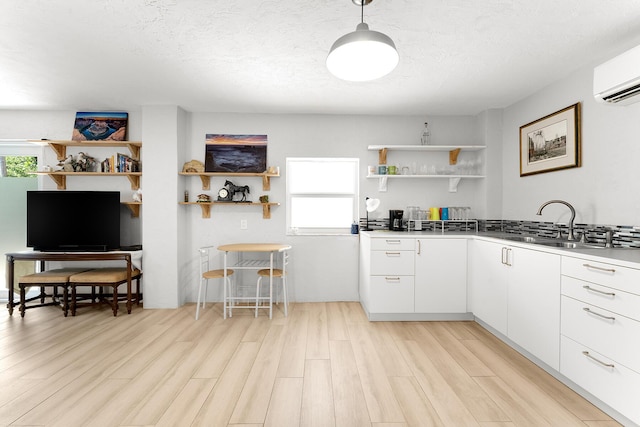 kitchen featuring white cabinetry, a wealth of natural light, light hardwood / wood-style floors, and a wall mounted AC