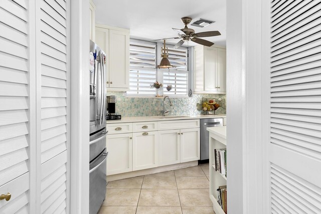 kitchen featuring sink, decorative light fixtures, light tile patterned floors, appliances with stainless steel finishes, and white cabinets