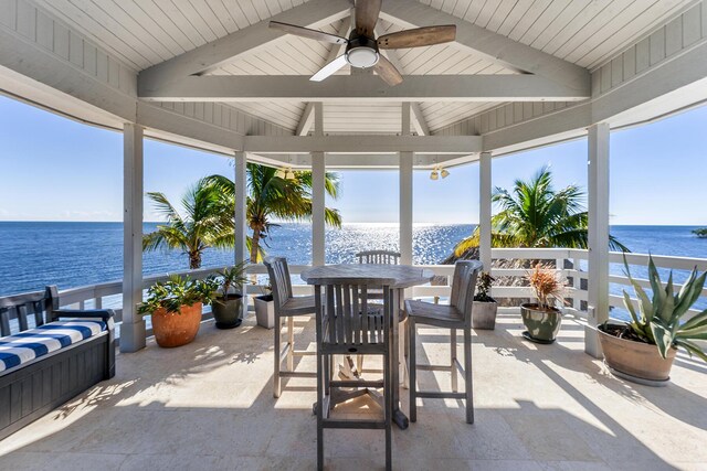 sunroom / solarium featuring a healthy amount of sunlight, a water view, and vaulted ceiling with beams