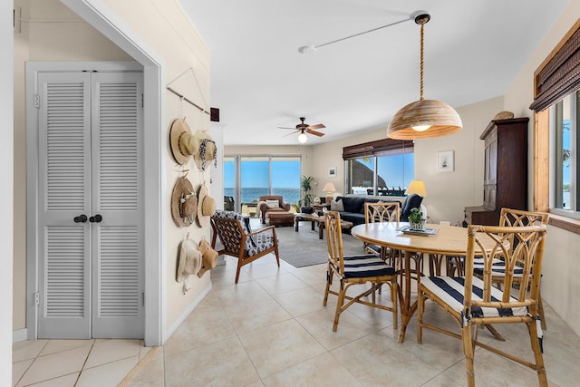 dining room with a water view, ceiling fan, and light tile patterned floors