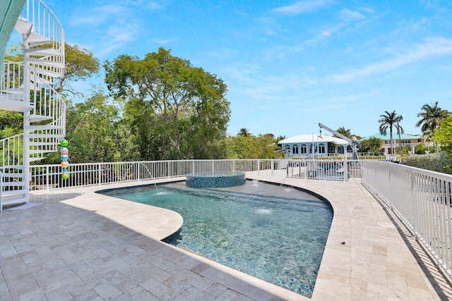 view of pool with a patio area, fence, and a pool with connected hot tub