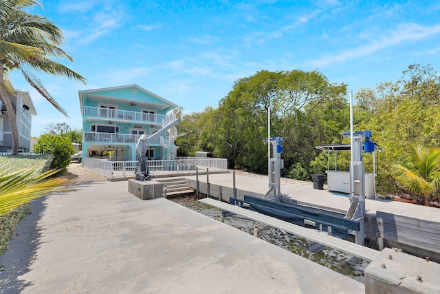 view of patio with boat lift, a boat dock, and a balcony