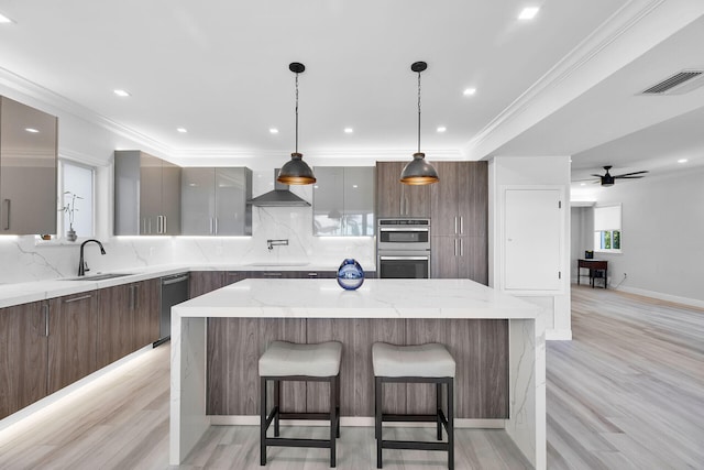 kitchen with modern cabinets, a sink, wall chimney exhaust hood, a spacious island, and light wood-style flooring