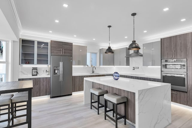 kitchen featuring stainless steel appliances, modern cabinets, a sink, backsplash, and ornamental molding