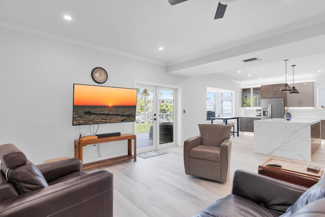living room with crown molding, plenty of natural light, light wood-style flooring, a ceiling fan, and recessed lighting