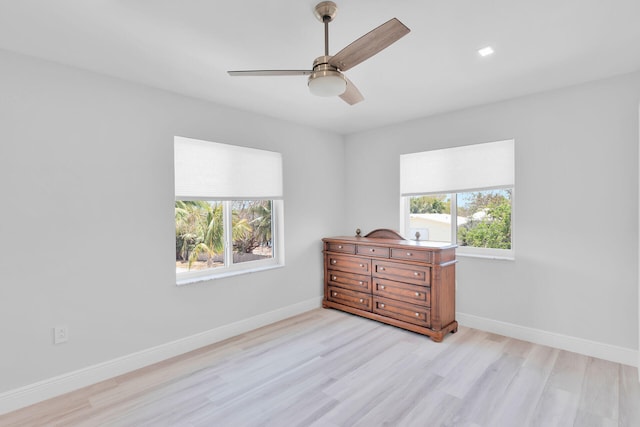 bedroom with multiple windows, light wood finished floors, and baseboards