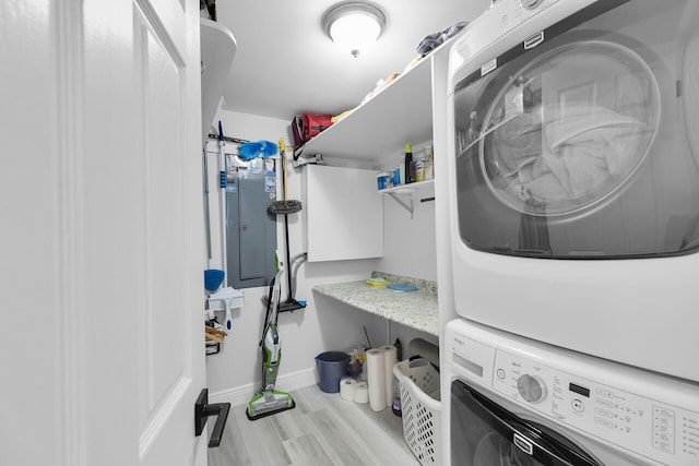 laundry room with estacked washer and dryer, baseboards, and wood finished floors
