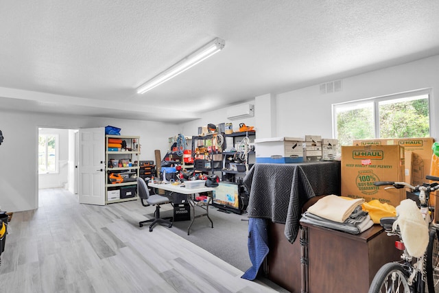 office area featuring a wall mounted air conditioner, a textured ceiling, plenty of natural light, and wood finished floors