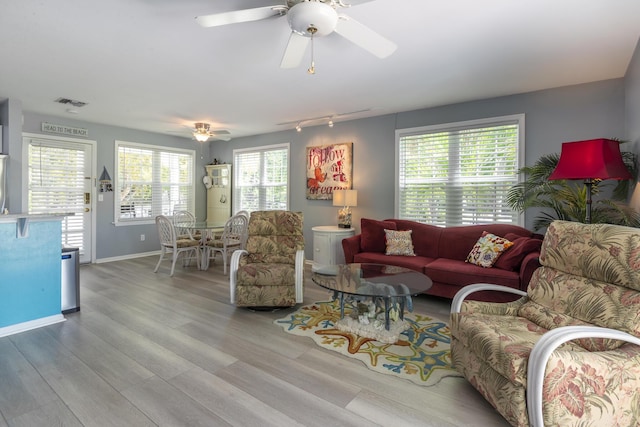 living room featuring a ceiling fan, wood finished floors, visible vents, and baseboards