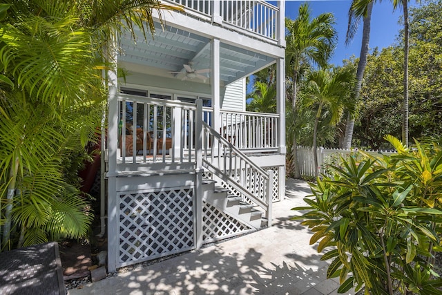 view of gate featuring stairs, a ceiling fan, and fence