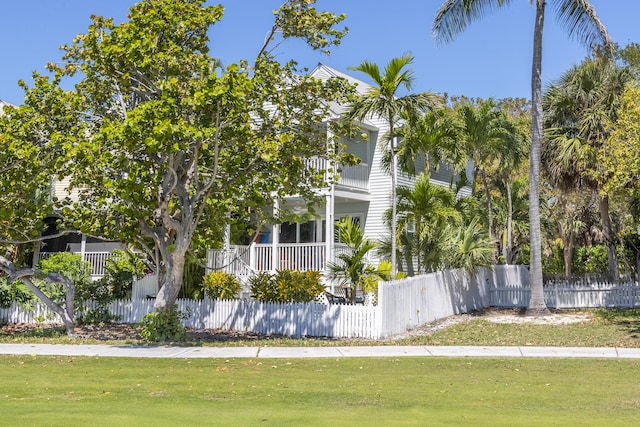 view of property exterior featuring a fenced front yard, a yard, and a balcony