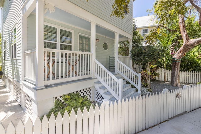 entrance to property with a porch and fence