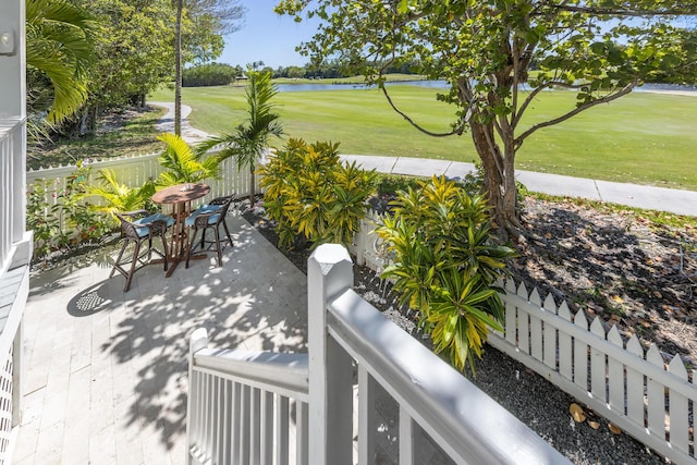 view of patio featuring outdoor dining area, a fenced backyard, a water view, and golf course view