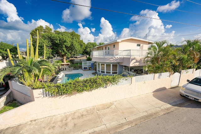 view of front of home with a balcony and a fenced in pool