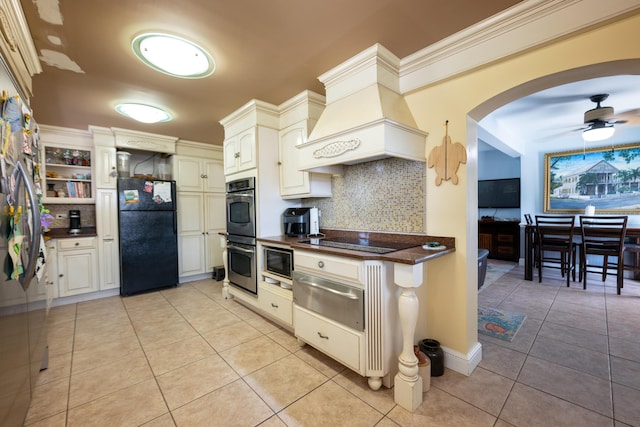 kitchen featuring custom exhaust hood, light tile patterned floors, ceiling fan, decorative backsplash, and black appliances