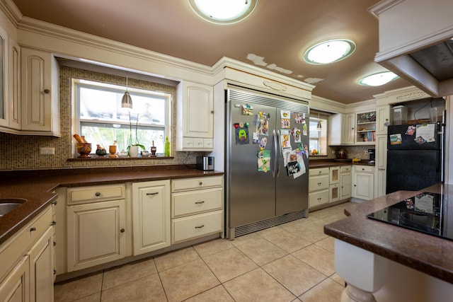 kitchen with tasteful backsplash, cream cabinets, light tile patterned floors, and black appliances