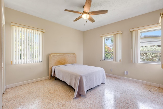 bedroom featuring a ceiling fan, baseboards, and speckled floor