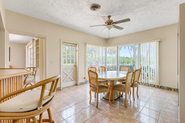 dining space with visible vents, a textured ceiling, baseboards, and ceiling fan