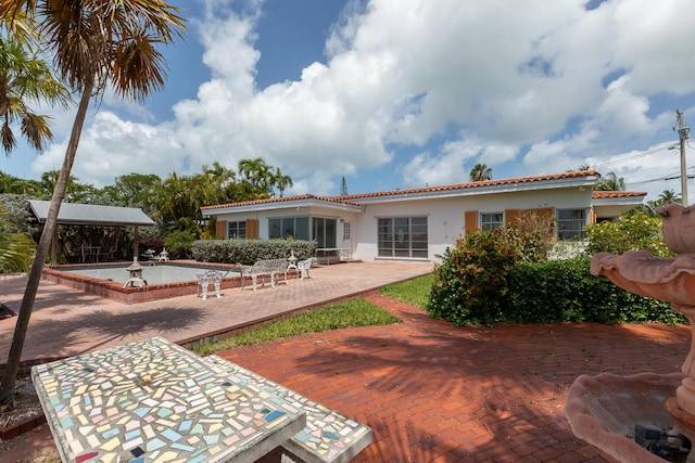 rear view of property featuring stucco siding, a patio area, and a tiled roof