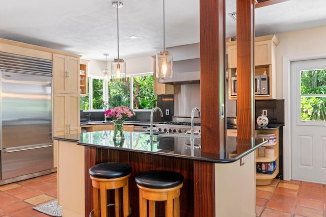 7563 Gulfstream Blvd, Marathon, FL 33050 - kitchen featuring appliances with stainless steel finishes, a kitchen breakfast bar, decorative light fixtures, light tile patterned floors, and an island with sink