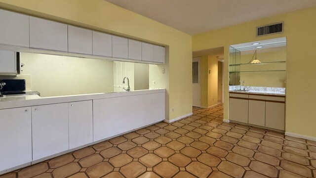 1800 Atlantic Blvd Unit C130, Key West, FL 33040 - kitchen featuring white cabinets, baseboards, light countertops, and a sink