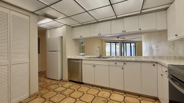 1800 Atlantic Blvd Unit C130, Key West, FL 33040 - kitchen with appliances with stainless steel finishes, a sink, light countertops, a paneled ceiling, and a ceiling fan