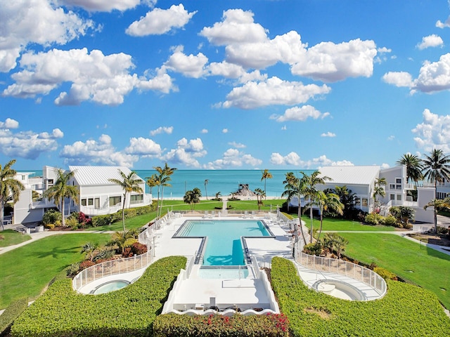 view of swimming pool with a patio, a water view, and a yard