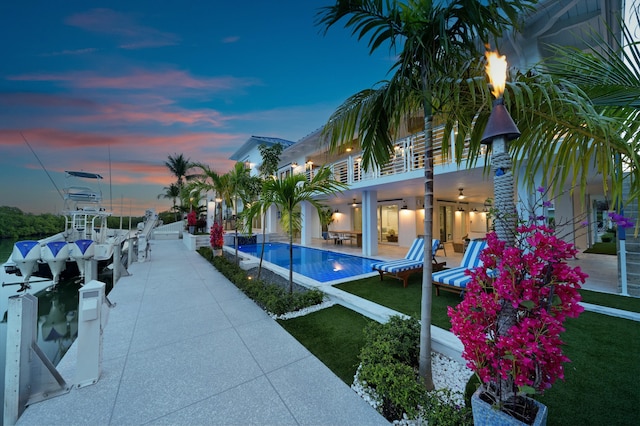 pool at dusk with a yard and a patio area