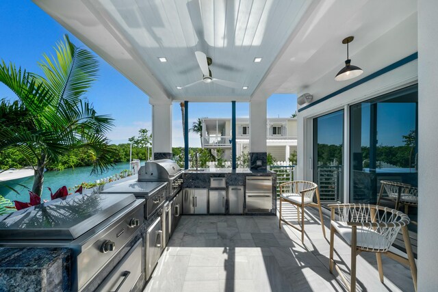 view of patio / terrace featuring grilling area, a water view, ceiling fan, and exterior kitchen