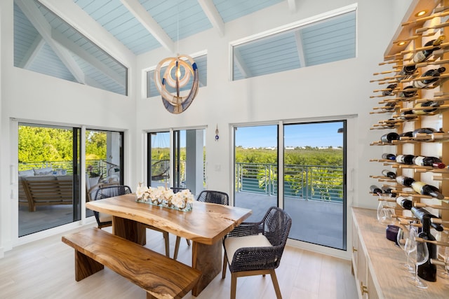 dining room with beamed ceiling, high vaulted ceiling, and light wood-type flooring