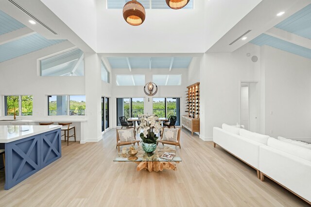 dining space with beamed ceiling, sink, high vaulted ceiling, and light wood-type flooring