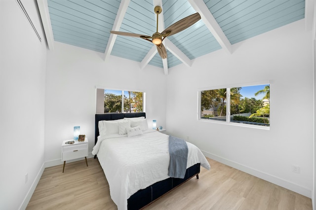 bedroom featuring ceiling fan, vaulted ceiling with beams, and light wood-type flooring