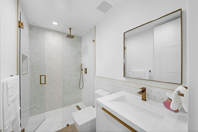 bathroom with vanity, tiled shower, and toilet