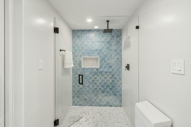 bathroom with an enclosed shower, toilet, and tile walls