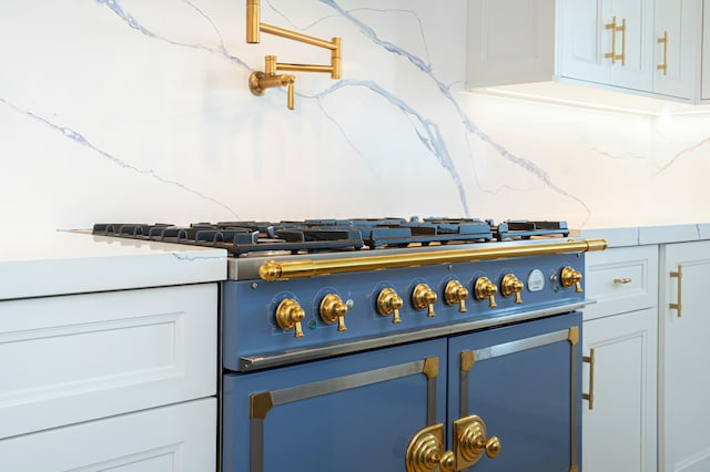 interior details featuring tasteful backsplash, white cabinetry, and stove