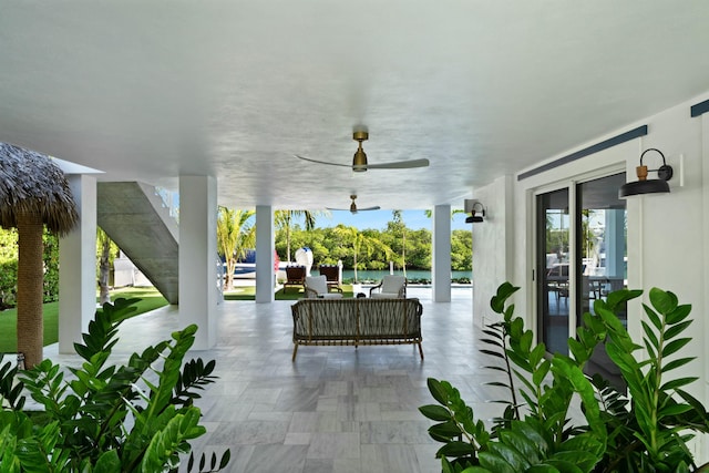 view of patio / terrace featuring a water view, ceiling fan, and an outdoor living space