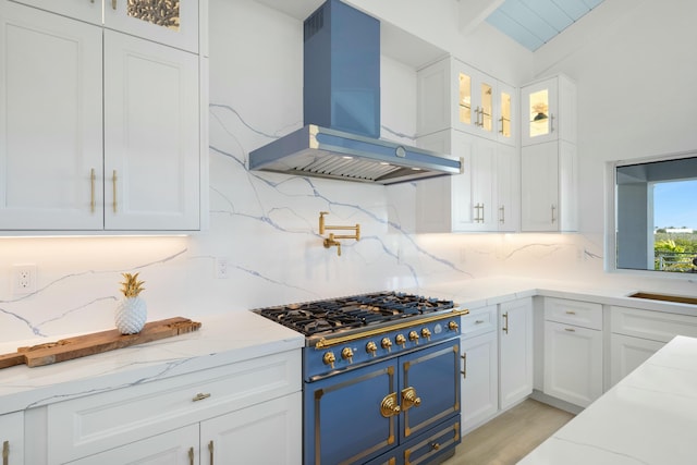 kitchen with tasteful backsplash, white cabinets, exhaust hood, light stone counters, and cooktop