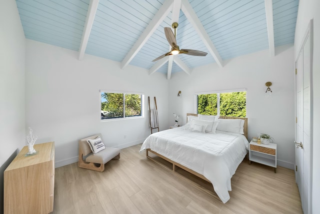 bedroom featuring multiple windows, lofted ceiling with beams, and light hardwood / wood-style floors