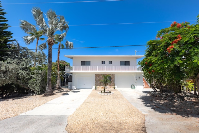 321 Calzada De Bougainville, Marathon, FL 33050 - view of front facade featuring driveway, a garage, stone siding, and a balcony