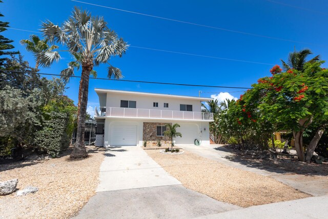 321 Calzada De Bougainville, Marathon, FL 33050 - view of front of property with a balcony, an attached garage, concrete driveway, stone siding, and stucco siding