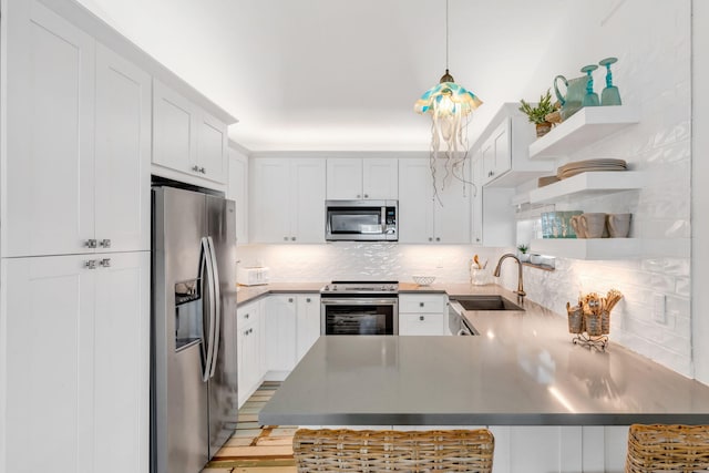 kitchen featuring a breakfast bar, sink, decorative light fixtures, stainless steel appliances, and white cabinets