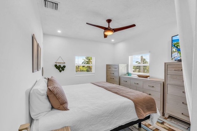 bedroom featuring multiple windows, a textured ceiling, and ceiling fan