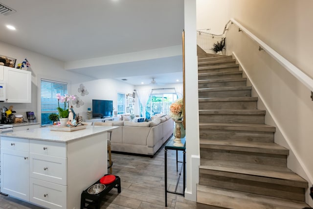 stairway with ceiling fan, visible vents, wood finished floors, and recessed lighting