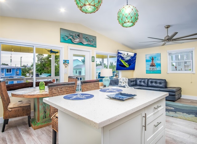 kitchen featuring pendant lighting, lofted ceiling, white cabinetry, light hardwood / wood-style floors, and a kitchen island