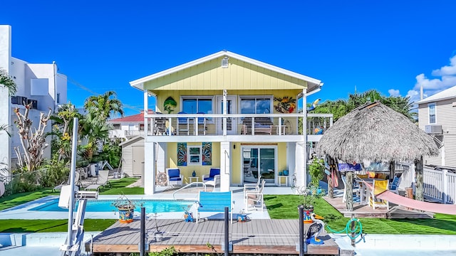 rear view of house featuring a lawn, a gazebo, a patio area, a storage unit, and a balcony