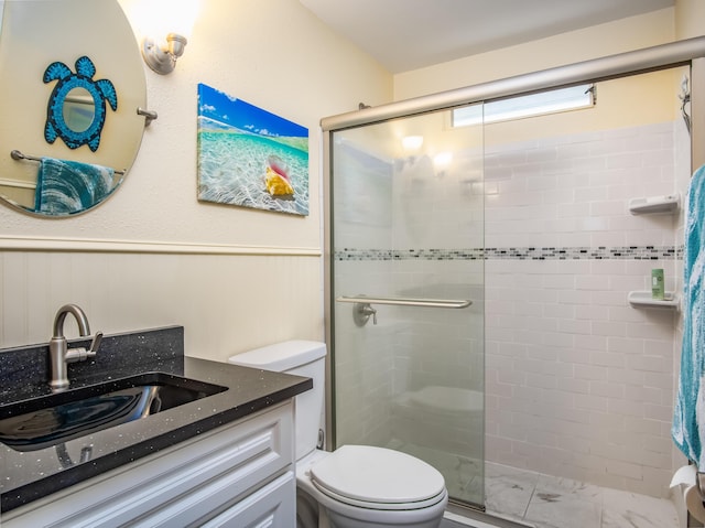 bathroom featuring vanity, a shower with shower door, and toilet