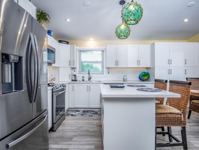 kitchen featuring sink, decorative light fixtures, appliances with stainless steel finishes, a kitchen breakfast bar, and a kitchen island