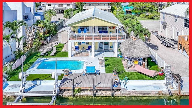 exterior space featuring a water view, a balcony, a fenced in pool, and a patio area